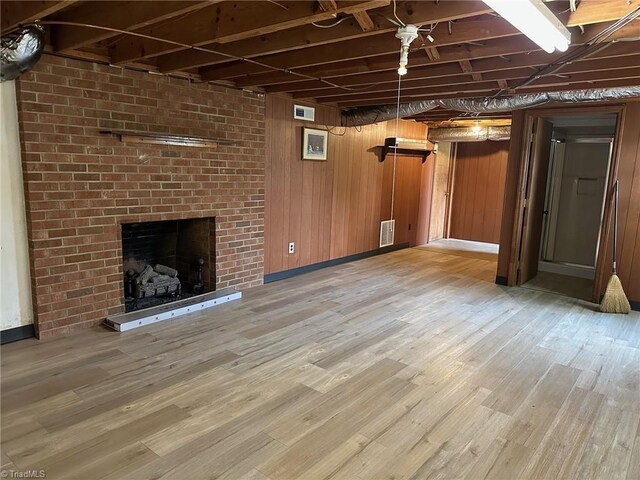 5912 US Highway 21, Jonesville, NC 28642 - unfurnished living room featuring light wood finished floors, a brick fireplace, and wooden walls