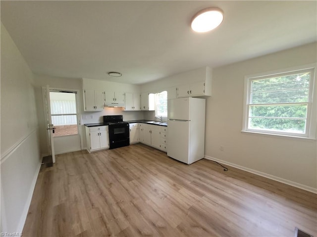 133 Lori Ln, Mount Airy, NC 27030 - kitchen featuring freestanding refrigerator, black stove, under cabinet range hood, dark countertops, and light wood-style flooring