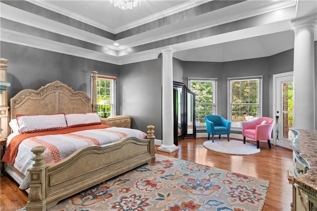 bedroom with decorative columns, wood finished floors, ornamental molding, and baseboards