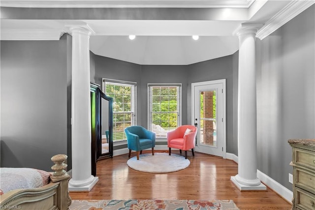 living area featuring ornate columns, plenty of natural light, ornamental molding, and wood finished floors