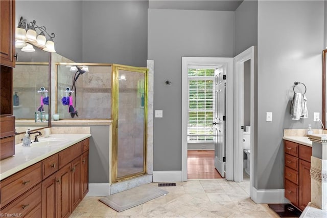 full bath featuring a stall shower, vanity, toilet, and baseboards