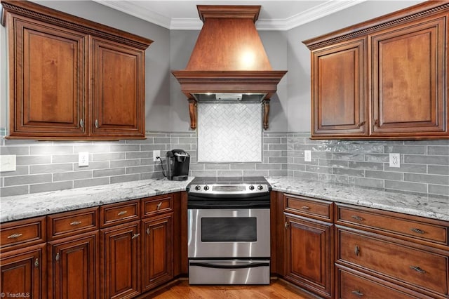kitchen with electric range, premium range hood, ornamental molding, light stone counters, and tasteful backsplash