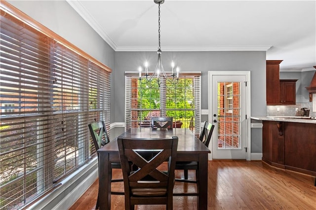 dining area with wood finished floors, a chandelier, and crown molding