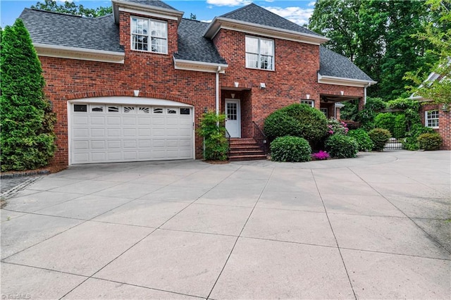 view of front of house featuring driveway, brick siding, and a shingled roof