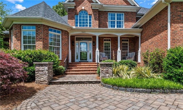 property entrance with covered porch and brick siding