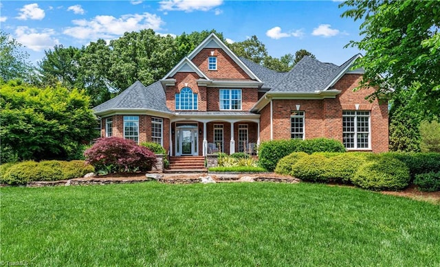 colonial inspired home featuring brick siding, a front yard, and a porch