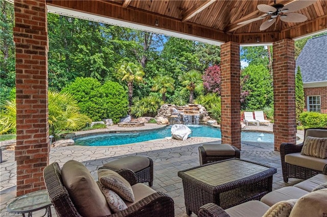 view of patio with a ceiling fan, an outdoor hangout area, an outdoor pool, and view of scattered trees
