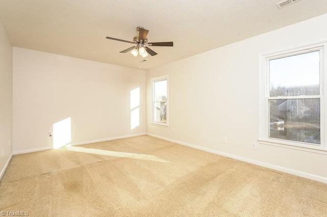 carpeted empty room featuring a wealth of natural light and ceiling fan