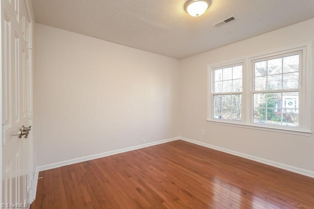 unfurnished room featuring hardwood / wood-style floors and a textured ceiling