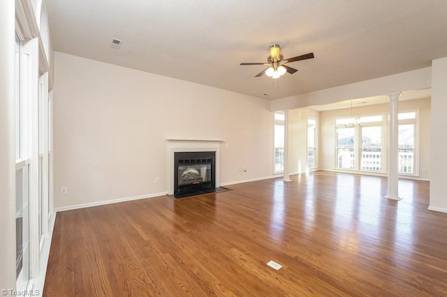 unfurnished living room with decorative columns, wood-type flooring, and ceiling fan