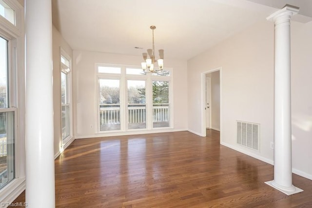 unfurnished dining area with an inviting chandelier, dark hardwood / wood-style floors, and ornate columns