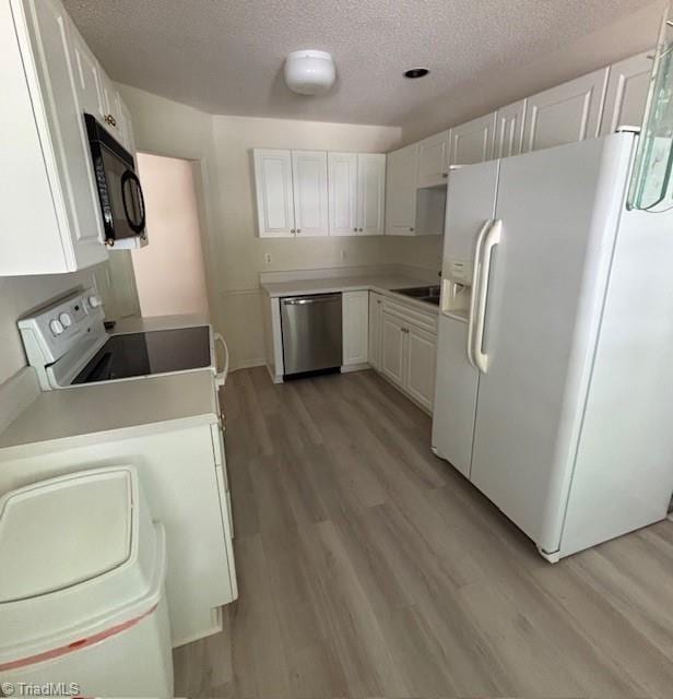 9 Whitdale Pt, Greensboro, NC 27455 - kitchen featuring white appliances, light wood-style floors, a textured ceiling, white cabinets, and light countertops