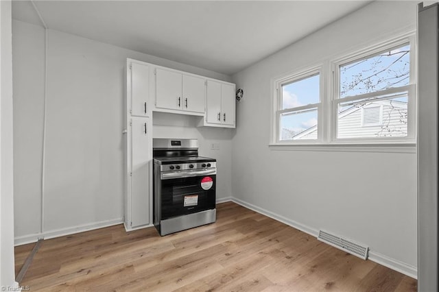 kitchen featuring baseboards, visible vents, light wood finished floors, white cabinets, and electric stove