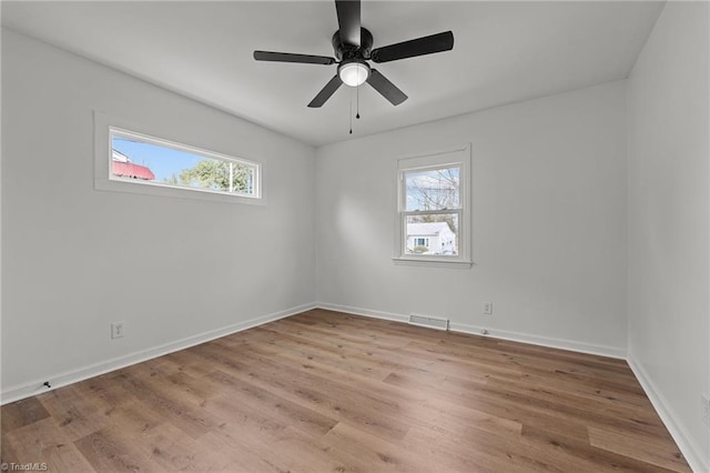 spare room with visible vents, a ceiling fan, baseboards, and wood finished floors