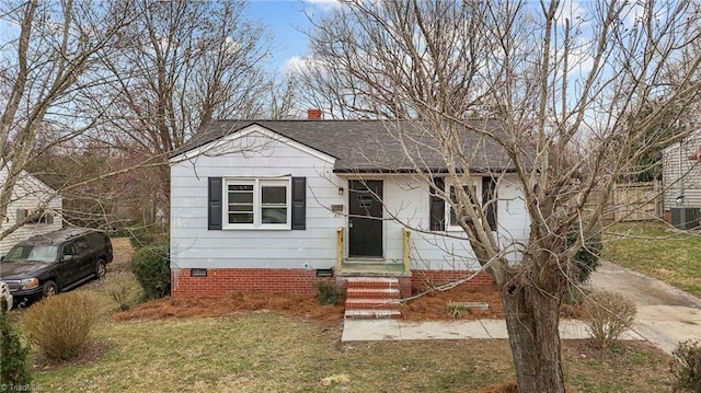 bungalow-style home with a front lawn, cooling unit, a shingled roof, crawl space, and a chimney