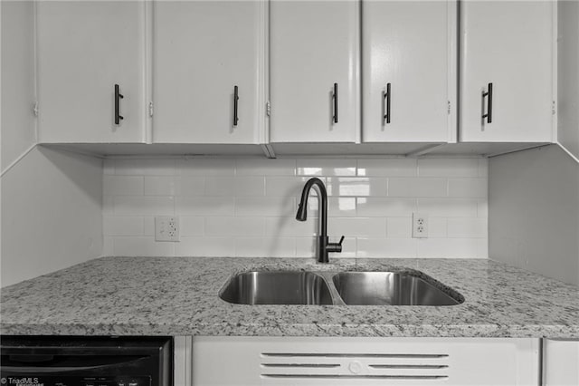 room details featuring light stone counters, white cabinetry, and a sink