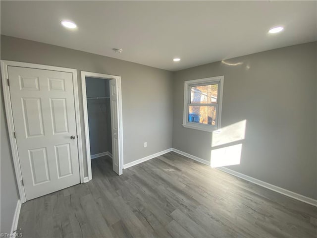 unfurnished bedroom featuring wood-type flooring, a spacious closet, and a closet