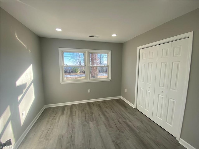 unfurnished bedroom with dark hardwood / wood-style floors and a closet