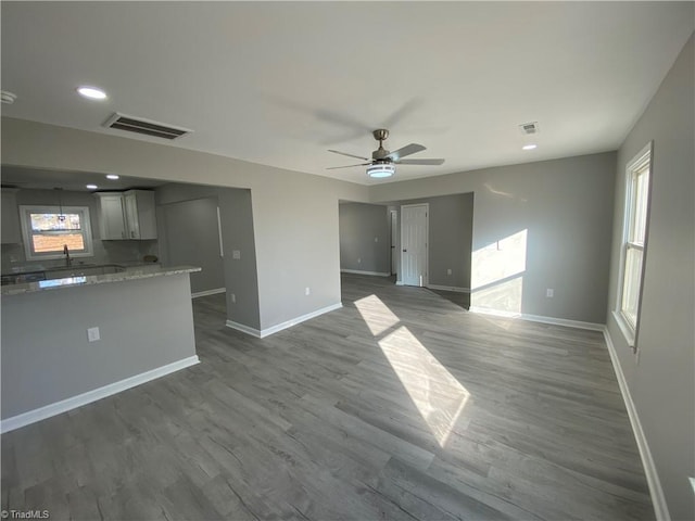 unfurnished living room featuring wood-type flooring, a wealth of natural light, and ceiling fan