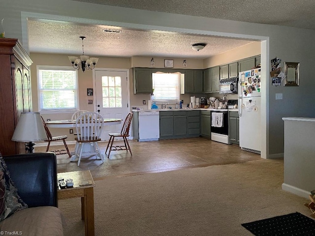 7533 Greenmeadow Dr, Tobaccoville, NC 27050 - kitchen with white appliances, light countertops, healthy amount of natural light, a chandelier, and a textured ceiling