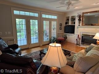 105 Finborough Ct, Kernersville, NC 27284 - living area featuring a glass covered fireplace, wood finished floors, a ceiling fan, and french doors