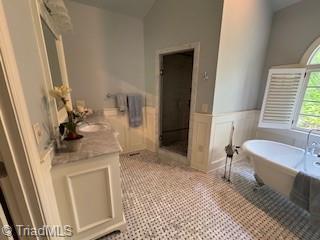 105 Finborough Ct, Kernersville, NC 27284 - bathroom with lofted ceiling, a soaking tub, a wainscoted wall, and vanity