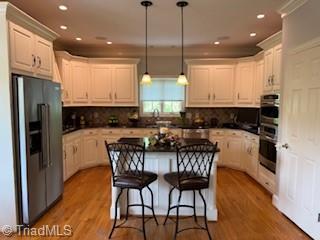 105 Finborough Ct, Kernersville, NC 27284 - kitchen with a breakfast bar, a kitchen island, tasteful backsplash, hanging light fixtures, and refrigerator with ice dispenser