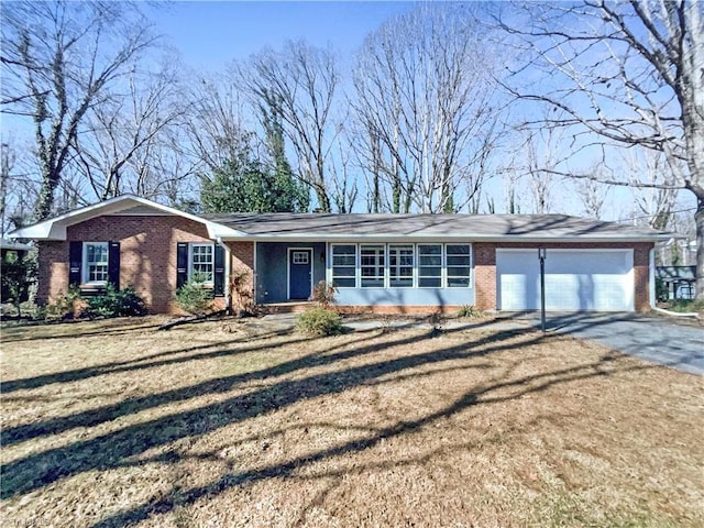 ranch-style home with driveway, brick siding, an attached garage, and a front yard