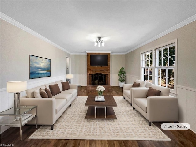 living area featuring ornamental molding, a wainscoted wall, a fireplace, and wood finished floors