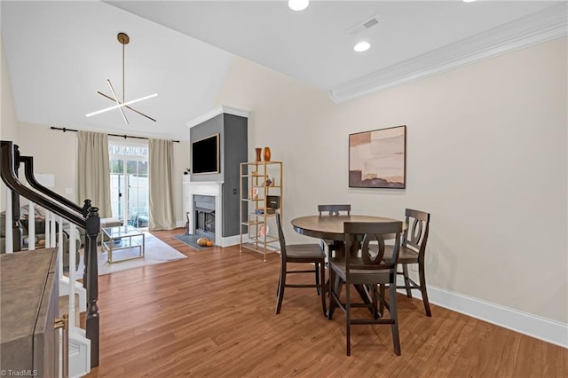 dining area with hardwood / wood-style flooring, an inviting chandelier, and crown molding