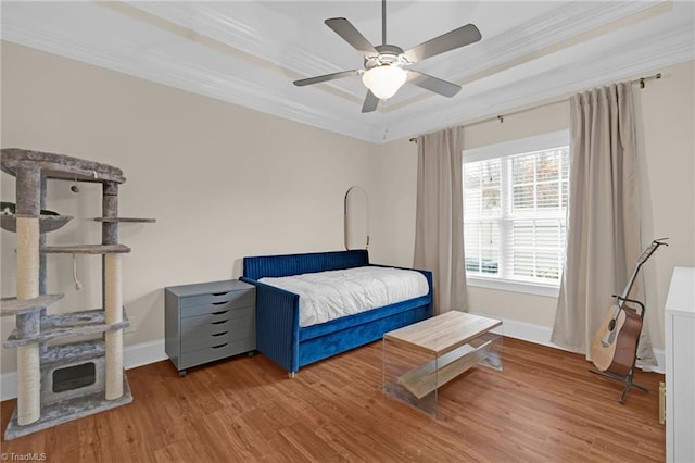 bedroom with a raised ceiling, ceiling fan, ornamental molding, and hardwood / wood-style flooring