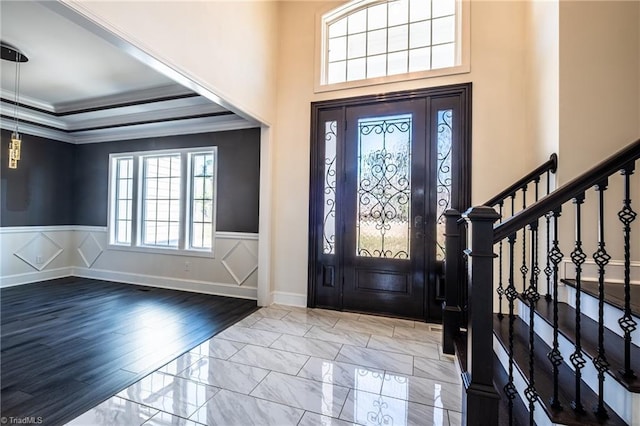 entryway with marble finish floor, stairway, wainscoting, and crown molding