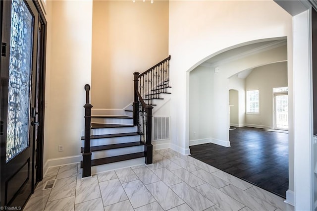 entryway with arched walkways, marble finish floor, visible vents, and baseboards