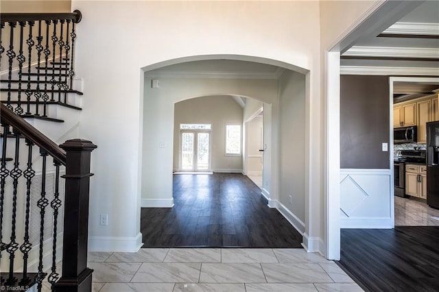 entryway with arched walkways, marble finish floor, crown molding, and stairs