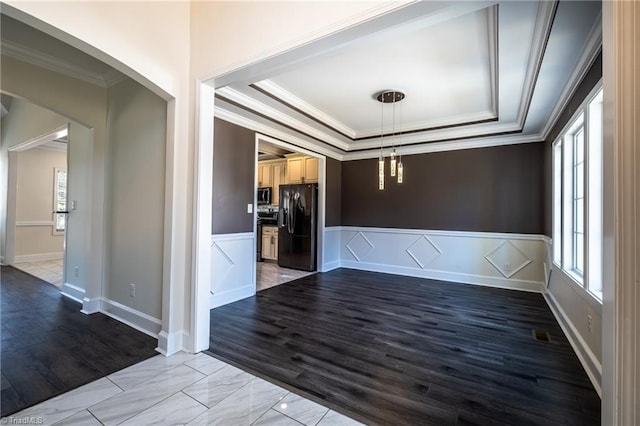 spare room featuring arched walkways, a wainscoted wall, a raised ceiling, and crown molding