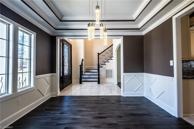 entrance foyer featuring arched walkways, wood finished floors, a raised ceiling, and visible vents