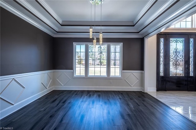 entrance foyer featuring a tray ceiling, dark wood-style flooring, and wainscoting