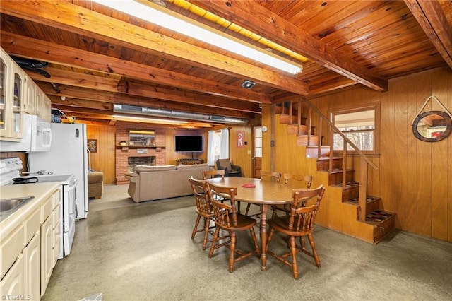 dining space featuring beam ceiling, a brick fireplace, and wooden walls