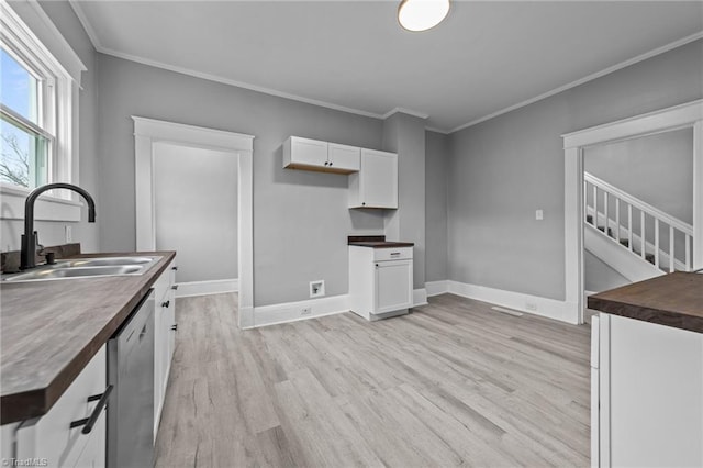 kitchen featuring sink, wooden counters, white cabinets, stainless steel dishwasher, and light wood-type flooring