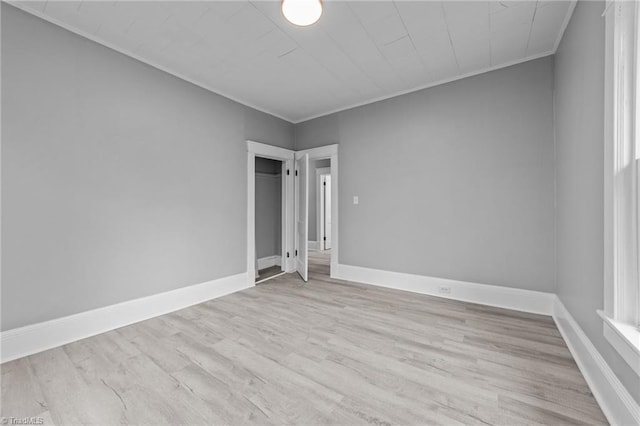 empty room featuring ornamental molding and light wood-type flooring