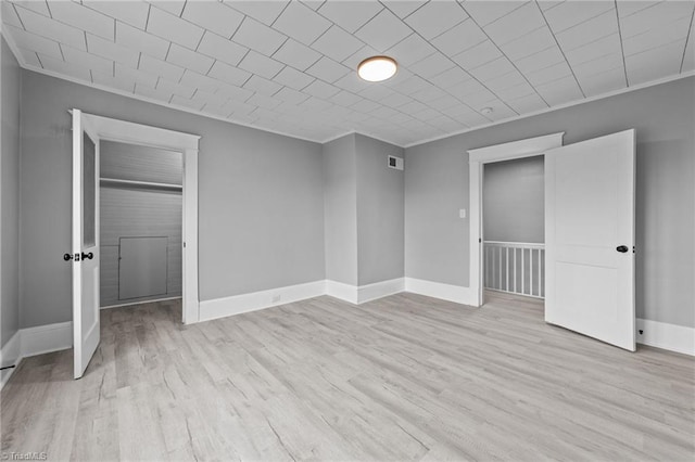 unfurnished bedroom featuring crown molding and light wood-type flooring