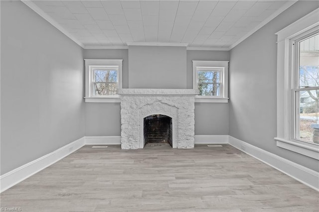 unfurnished living room featuring ornamental molding, a stone fireplace, and light hardwood / wood-style floors