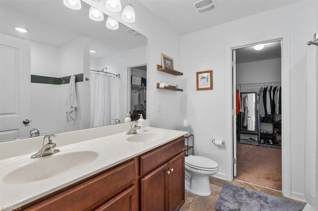 full bath featuring visible vents, a spacious closet, double vanity, and a sink