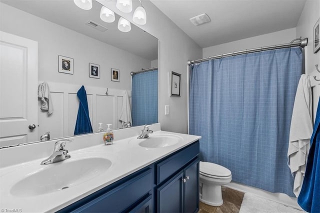 full bathroom featuring toilet, double vanity, a sink, and visible vents