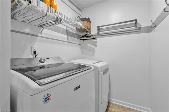 washroom featuring baseboards, light tile patterned flooring, separate washer and dryer, and laundry area