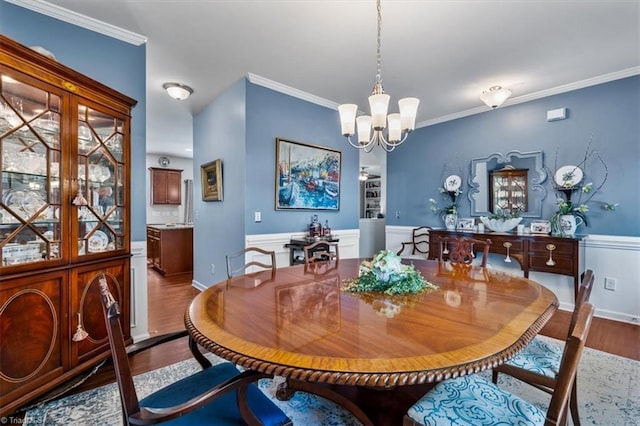 dining space with a chandelier, baseboards, wood finished floors, and crown molding