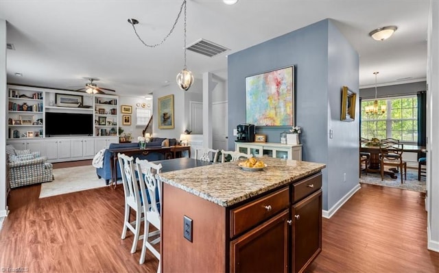 kitchen featuring a breakfast bar area, visible vents, ceiling fan, and dark wood-style flooring