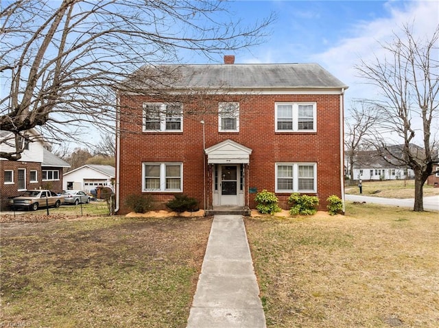 view of front facade featuring a front yard, brick siding, and a chimney