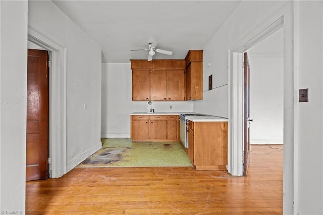 kitchen with light wood finished floors, brown cabinets, light countertops, and ceiling fan