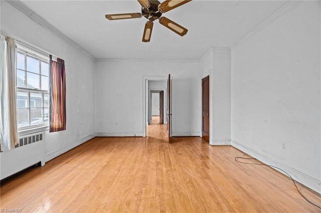 spare room featuring baseboards, radiator heating unit, ceiling fan, light wood-style floors, and crown molding